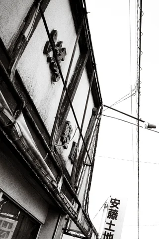 A tilted upward view shows raised wall lettering, a projecting lamp and overhead wires in black and white.