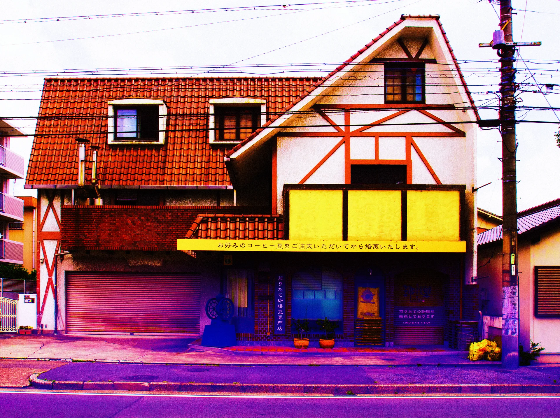 A steep gable with red trim rises above a yellow storefront panel beside a red tiled roof.