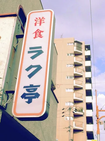 A tall pale restaurant sign with orange trim projects beside an apartment building.