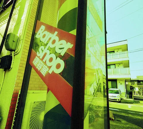 Bold pale Barber shop lettering marks a diagonal red panel beside a reflective window.