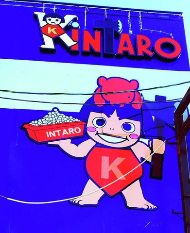 A smiling cartoon child holding a tray decorates a vivid blue wall beneath large red lettering.