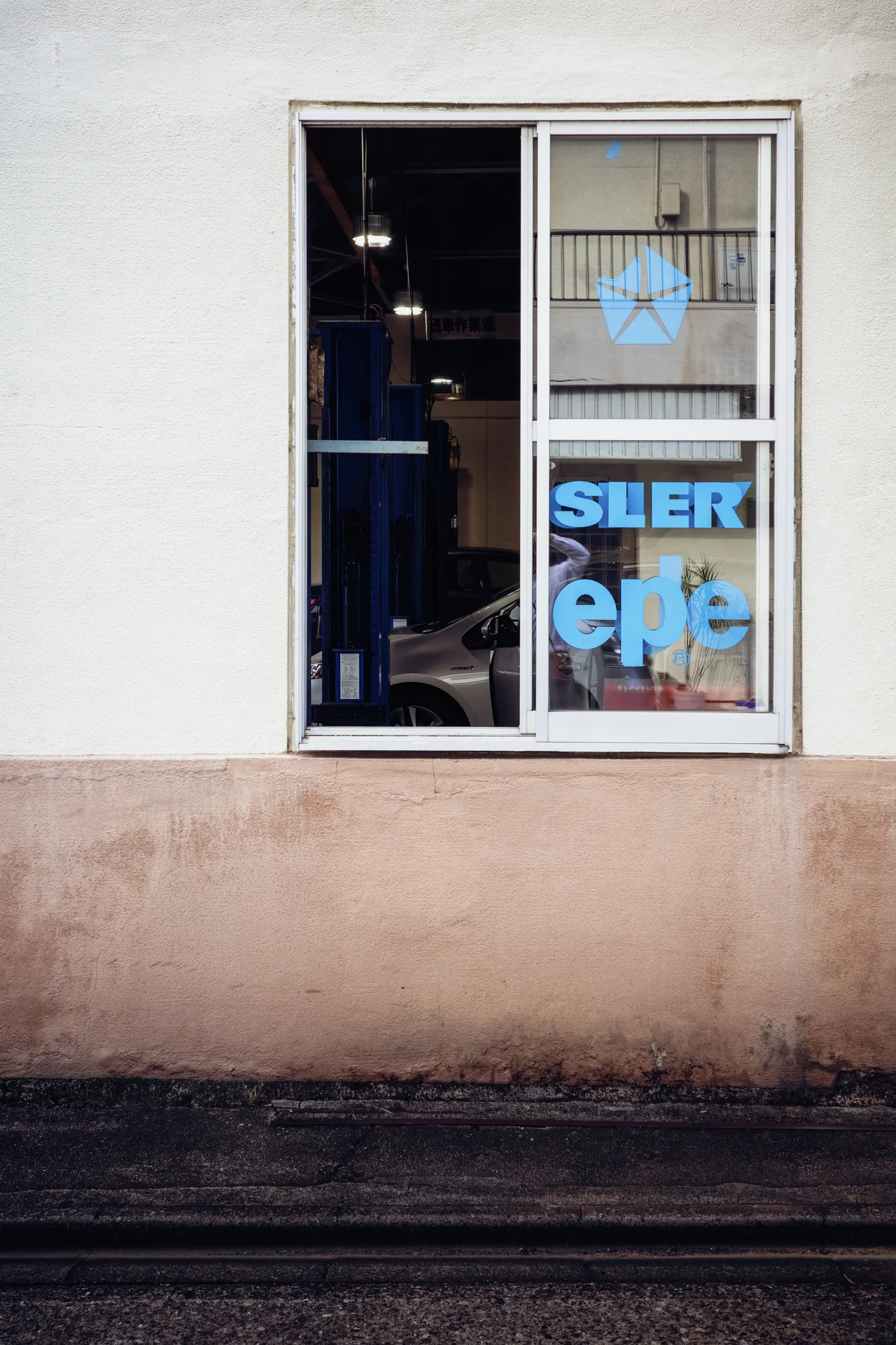 Blue lettering appears inside a narrow window set into a stained cream wall.