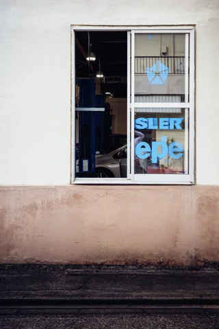 Blue lettering appears inside a narrow window set into a stained cream wall.