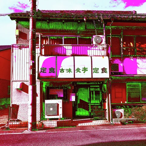 White Japanese sign panels span a brightly tinted restaurant frontage with exposed air-conditioning units and upper windows.