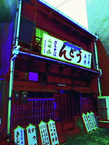 A white restaurant sign and small leaning menu boards decorate a dark wooden storefront with turquoise trim.
