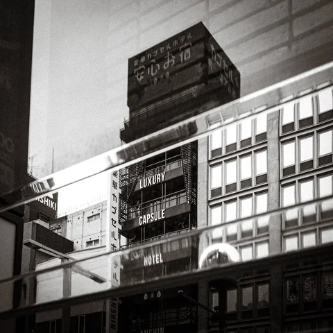 Reflections overlap a hotel facade with rows of windows and rooftop signage in monochrome.