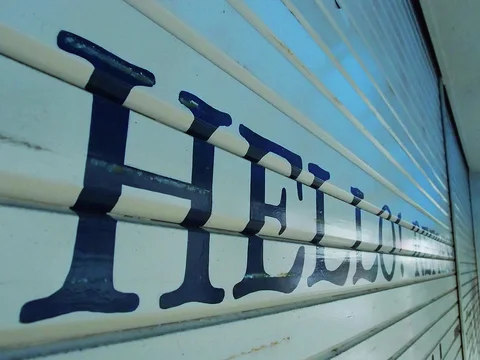 Large dark HELLO lettering stretches along a pale ribbed metal shutter viewed at a steep angle.