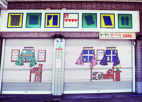 Colorful illustrated curtains and furnishings decorate closed shutters beneath a row of square graphic panels.