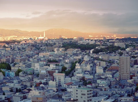 Warm light touches distant mountains above a dense foreground of white and gray city buildings.