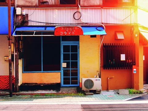A blue door and awning contrast with an orange storefront wall beside a barred window.