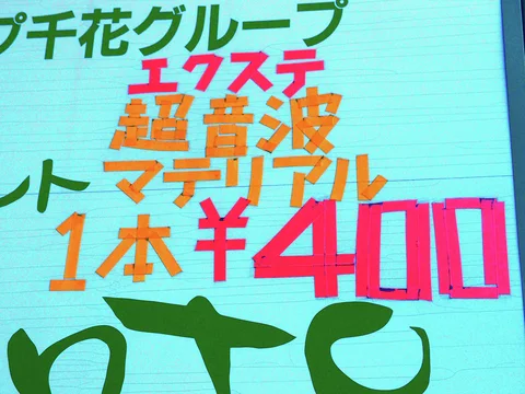 Large pink price numerals and orange characters fill a turquoise wall beneath green lettering.