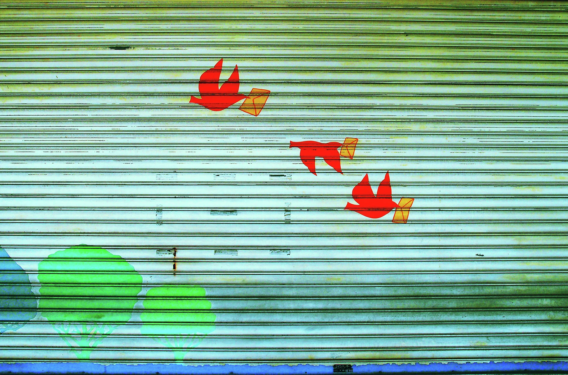 Three red birds carrying yellow shapes decorate a pale closed shutter above painted green foliage.