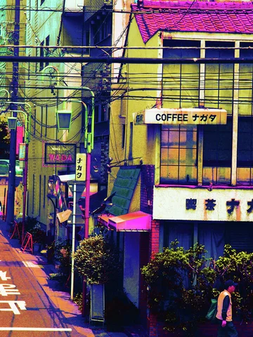 Overhead cables cross a narrow street lined with colorful shop fronts and small signs.