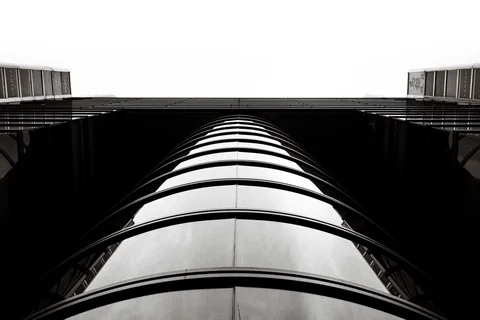 Repeating dark horizontal bands wrap a rounded tower viewed steeply upward in monochrome.