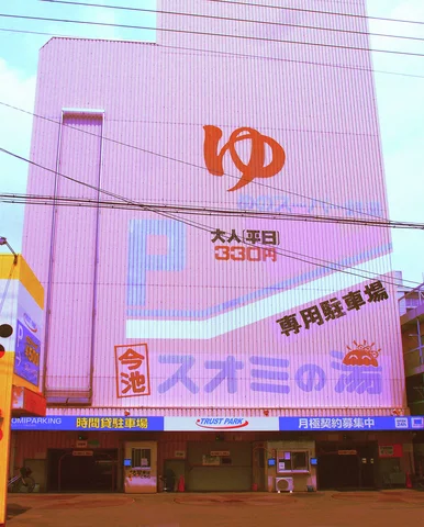 An orange symbol and large signs cover a pale building crossed by overhead utility wires.
