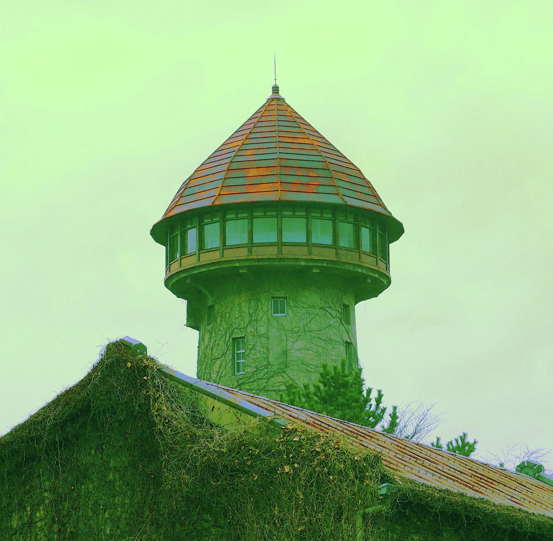 A cylindrical stone tower with a conical tiled roof rises above an ivy-covered sloping roof.