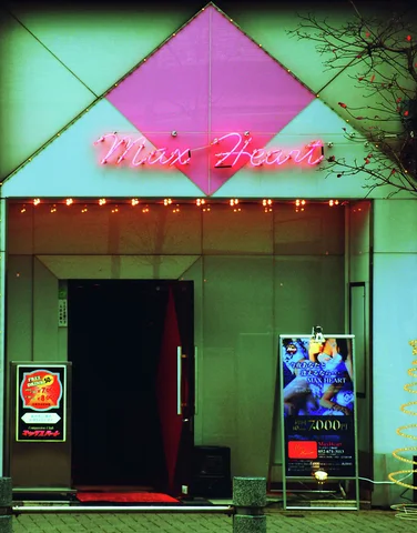 A dark recessed entrance sits beneath a large pink diamond panel and a row of bulbs.