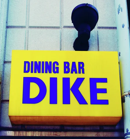 A bright yellow DINING BAR DIKE sign hangs beneath a black circular wall fixture.