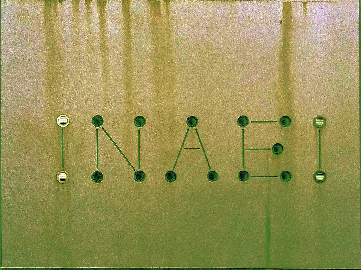 Small circular studs connected by thin lines form letters across a stained metal surface.