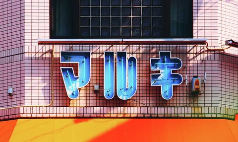 Large raised blue Japanese characters span a pink tiled facade above an orange awning.
