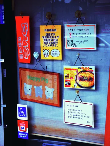 Colorful notices and a burger illustration cover a glass door beside accessibility and parking stickers.