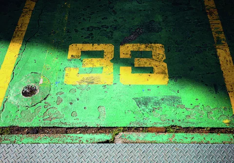 Yellow number 33 marks a worn green floor between yellow lines and a diamond-patterned metal threshold.