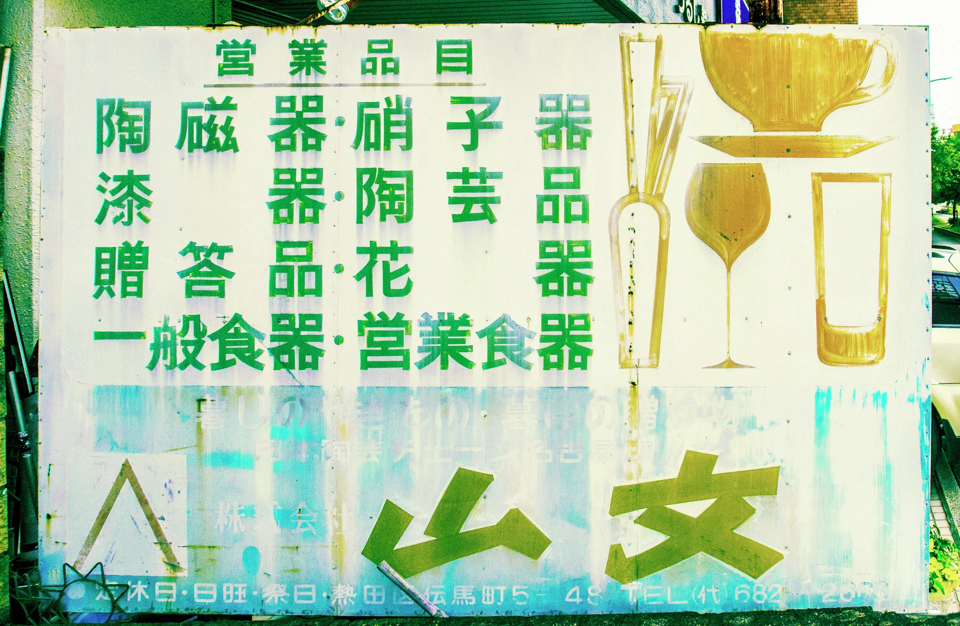 Green lettering and gold illustrations of bowls and glasses fill a weathered pale shop sign.