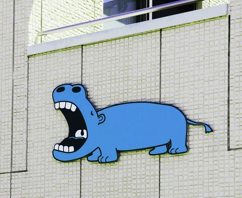 A cartoon blue hippopotamus with a wide open mouth decorates a pale tiled wall.