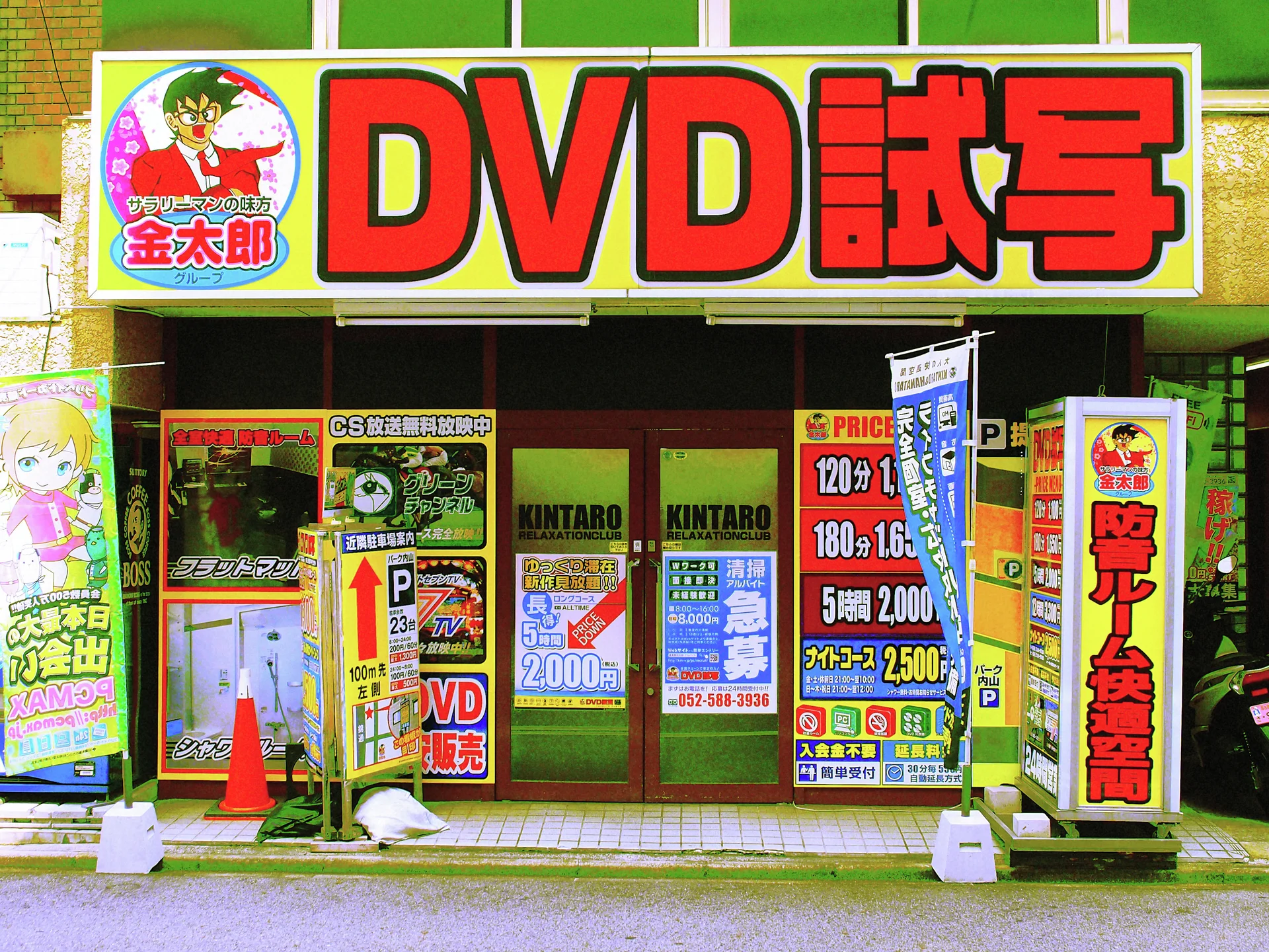 Bright red DVD lettering crowns a storefront crowded with colorful signs and orange traffic cones.