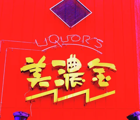 Yellow raised characters and thin LIQUOR'S lettering decorate a vivid red wall.