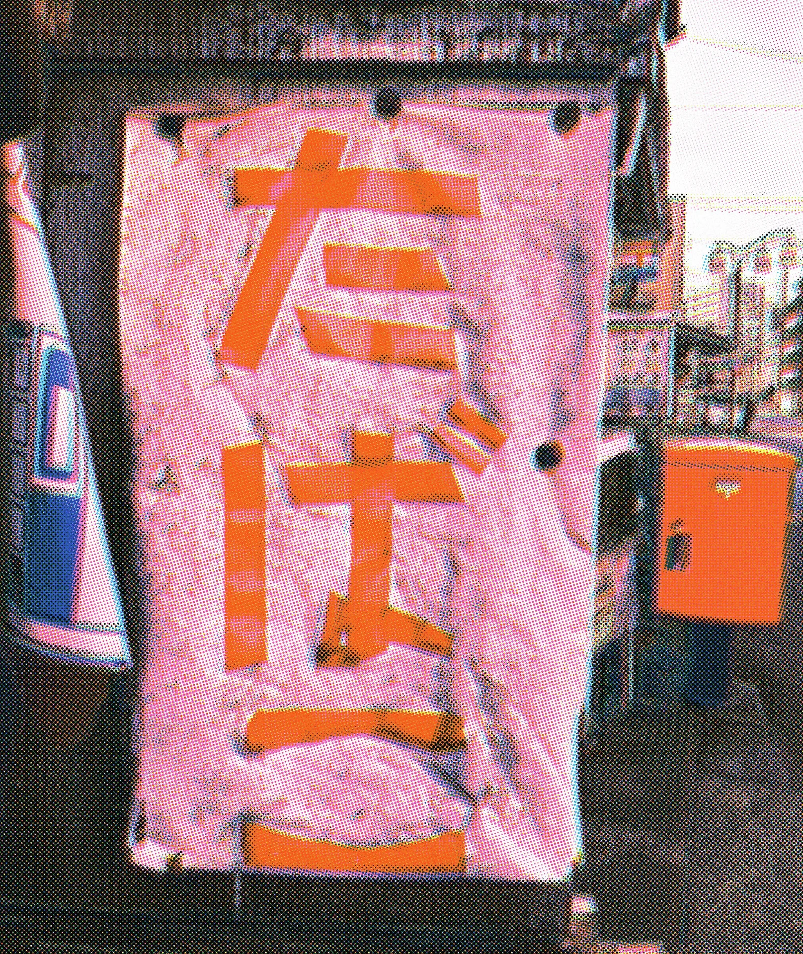 Large orange characters cover a weathered pink vertical sign beside an orange postbox.