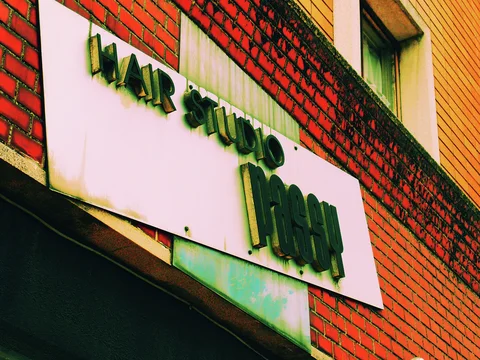 Raised dark lettering on a pale rectangular sign contrasts with the surrounding red brick facade.