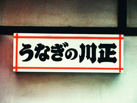 Bold black characters fill a pale rectangular restaurant sign within a thin red border.