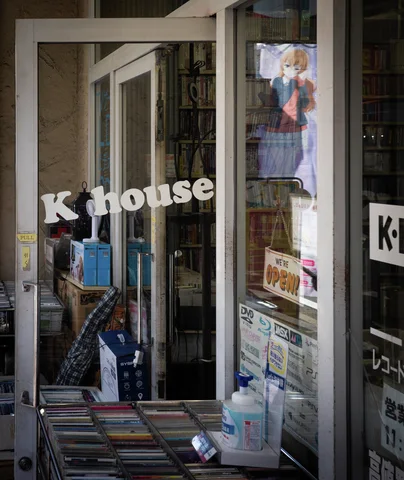 Books and posters crowd the glass entrance of a small shop with white lettering.