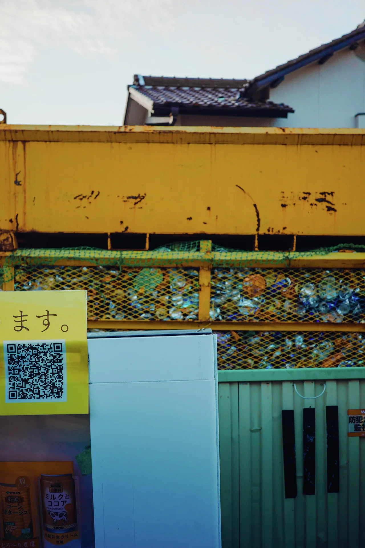 A yellow weathered fascia tops a storefront window with metal mesh and pale blue panels.