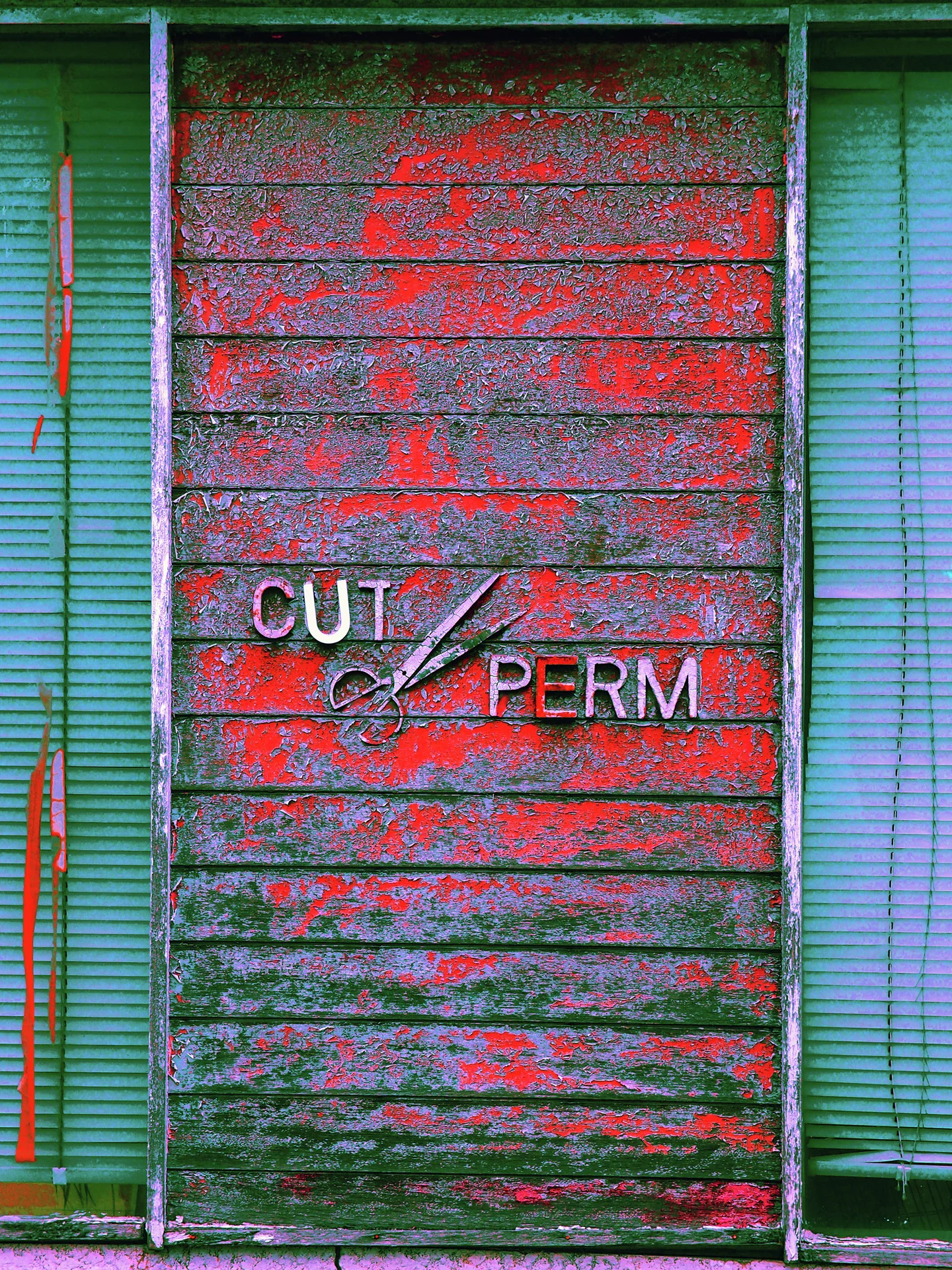 Small cut and perm lettering with a scissors motif decorates a weathered red and green slatted panel.
