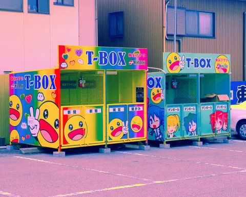 Colorful T-Box booths decorated with smiling cartoon faces stand side by side in a paved lot.