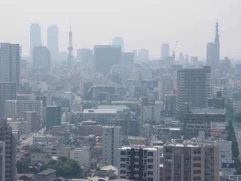 Tall distant towers fade into gray haze above layers of tightly packed city buildings.