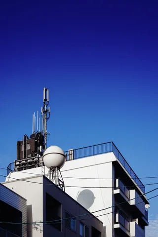 A spherical rooftop tank and antennas rise above a white building beneath clear deep blue sky.