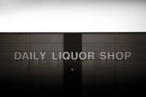 Raised DAILY LIQUOR SHOP lettering spans a broad paneled wall in black and white.