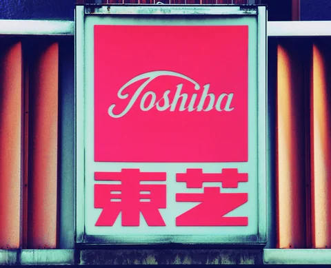 A pale-framed Toshiba sign combines a pink script panel and bold red Japanese characters.
