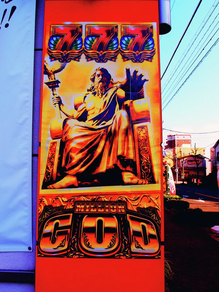 A tall orange-red poster depicts a seated robed figure above large metallic GOD lettering.