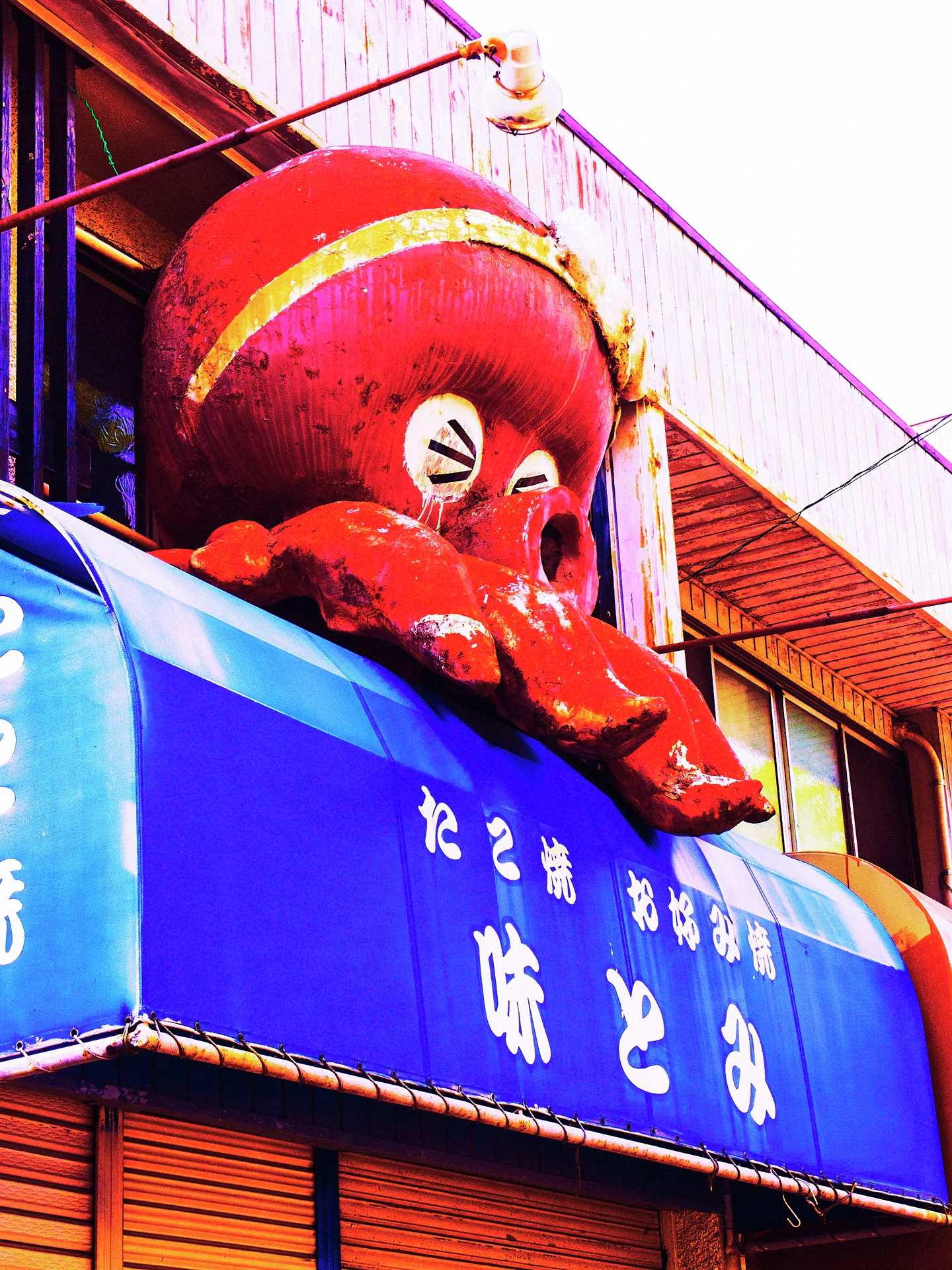 A large red cartoon octopus sits above a blue storefront awning with pale lettering.