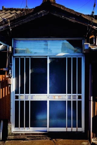 Bright blue sliding doors with white metal bars sit beneath a dark gabled tiled roof.