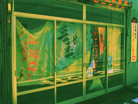Large printed banners hang behind green-tinted glass sliding doors with pale metal frames.