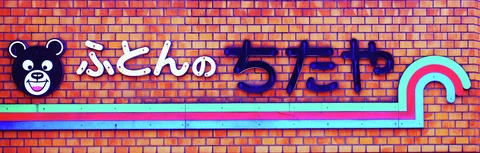 A smiling bear emblem and raised lettering decorate brickwork above turquoise and pink stripes.