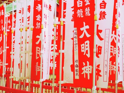 Closely spaced red and white vertical banners display bold Japanese characters on pale poles.