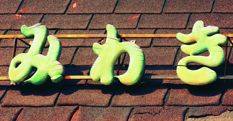 Three rounded pale green characters are mounted across reddish rectangular wall tiles.