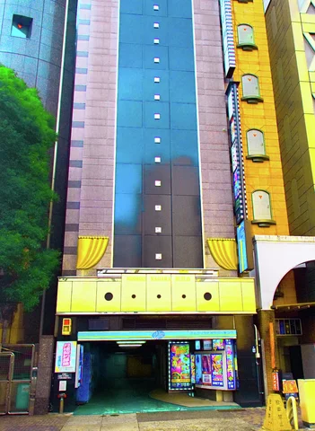 A tall teal facade with small square accents rises above a yellow-trimmed entrance and colorful posters.