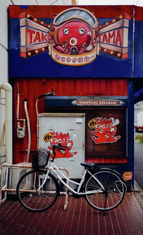 A white bicycle rests outside a red and blue storefront decorated with a cartoon octopus sign.